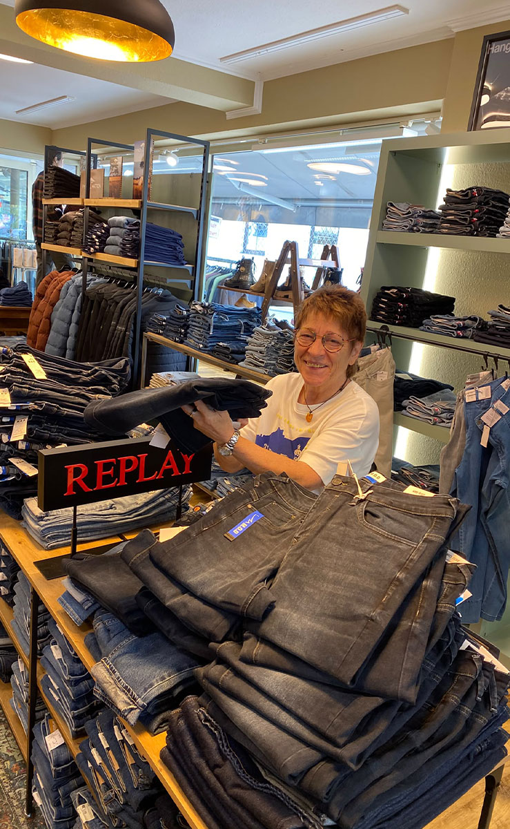 Mitarbeiterin im JEANS HOUSE Olching beim Auspacken und Pr&auml;sentieren neuer REPLAY Jeans im Gesch&auml;ft.